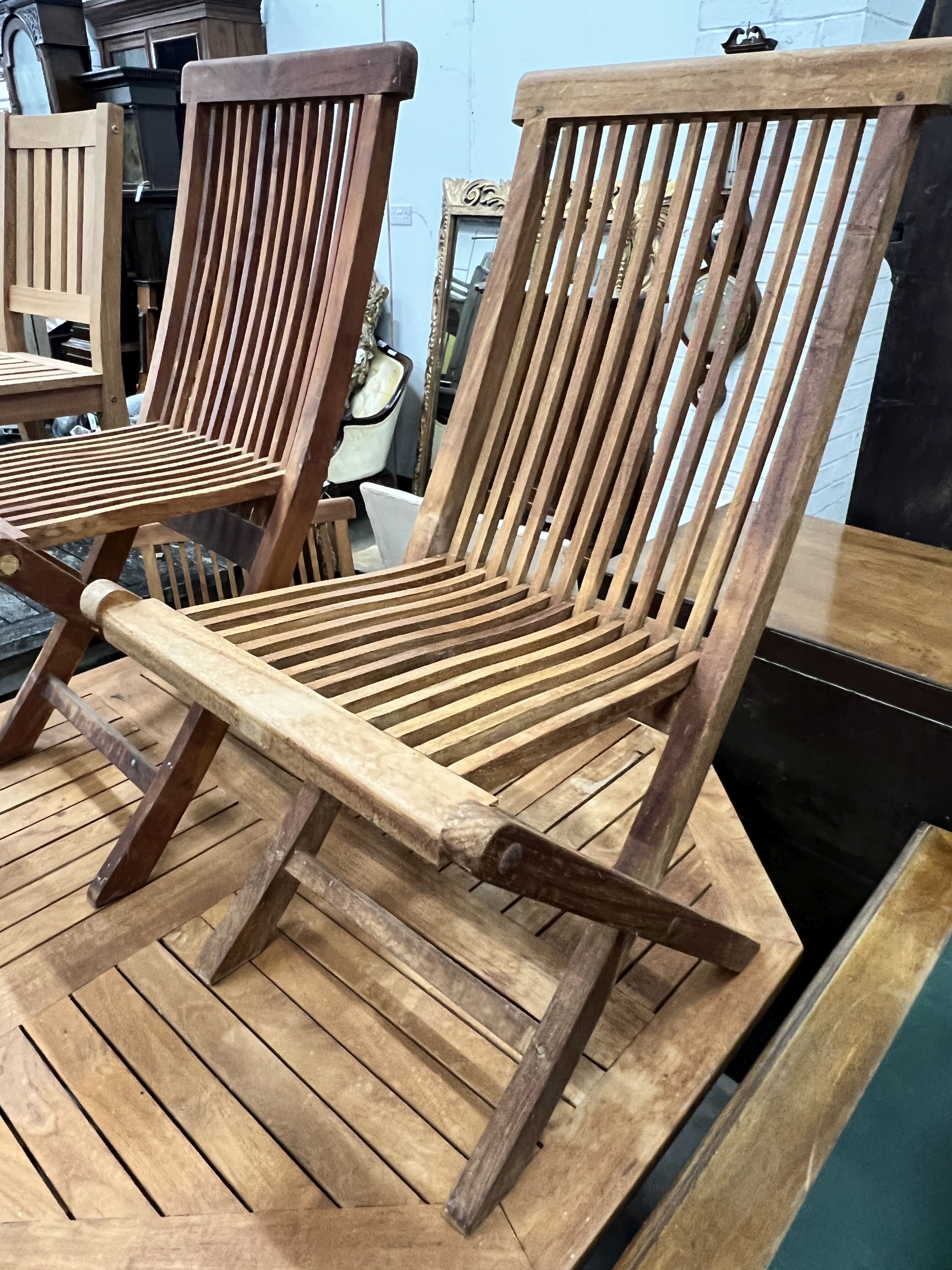 An octagonal teak folding garden table, length 120cm, height 74cm and four folding teak garden chairs, two with arms